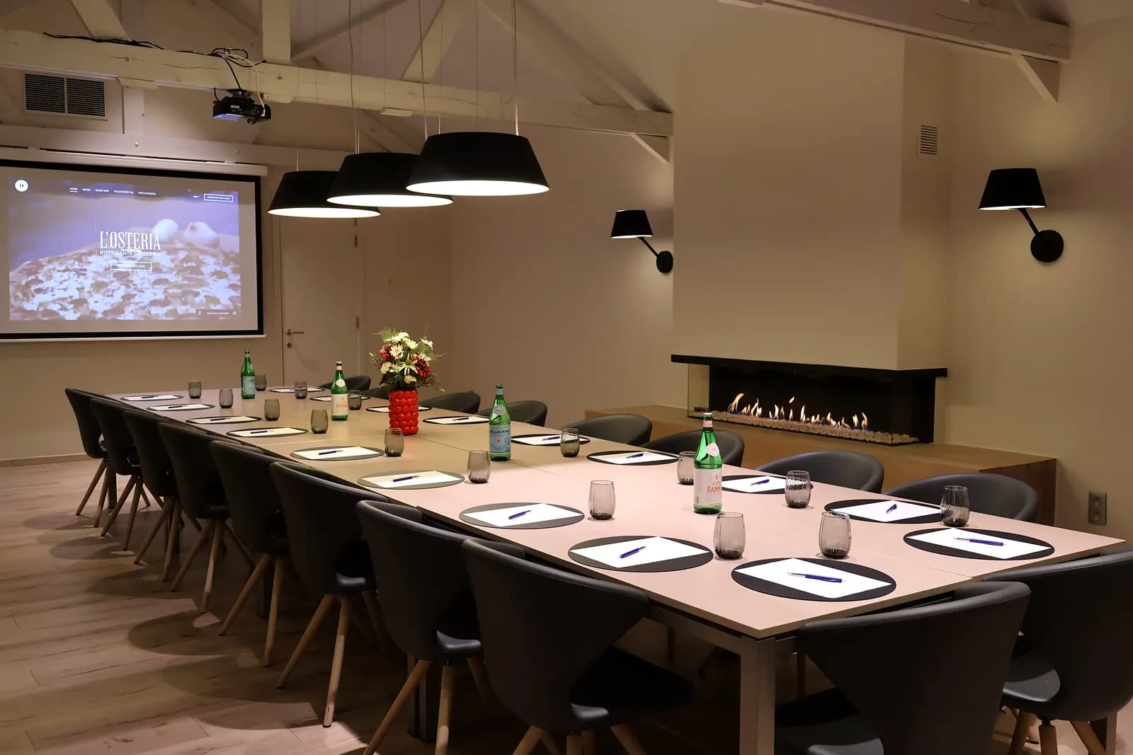 Long meeting table with projection screen and gas fireplace in L'Osteria's meeting room