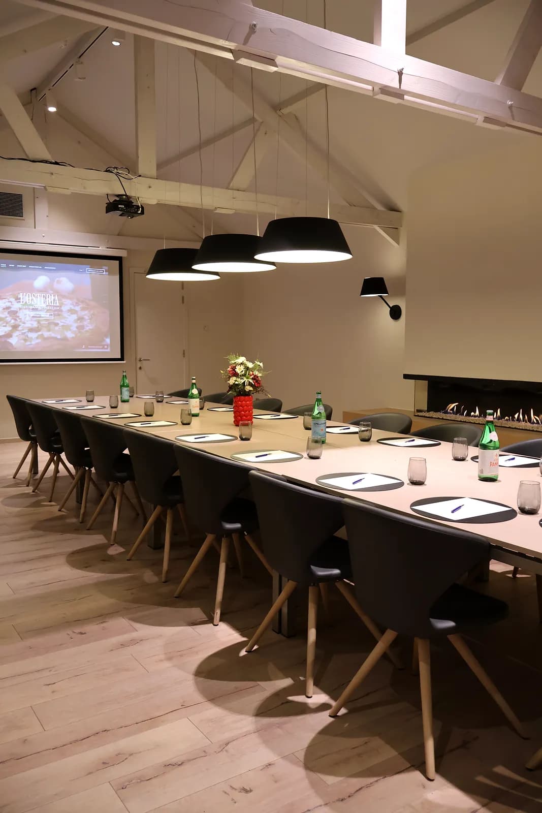 Meeting room under exposed wooden beams, with projector and screen